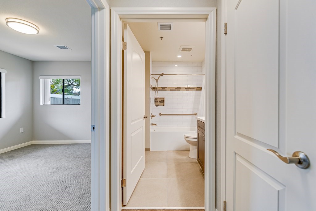 A bathroom with a toilet, sink, and shower is visible through an open door.