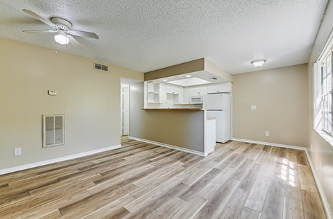 A room with a ceiling fan and a kitchenette.