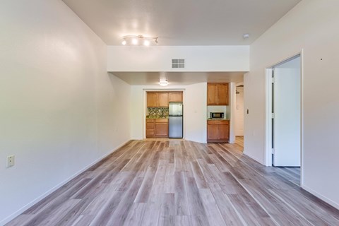 A spacious room with wooden flooring and white walls.