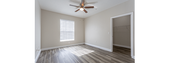 A room with a ceiling fan and a window with blinds.