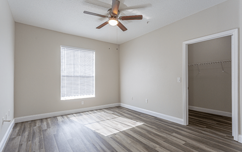 A room with a ceiling fan and a window with blinds.