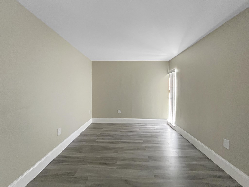 A room with a wooden floor and a window on the right side.