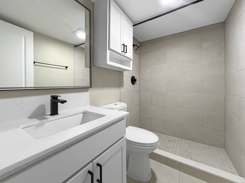 A white bathroom with a sink, toilet, and a mirror.