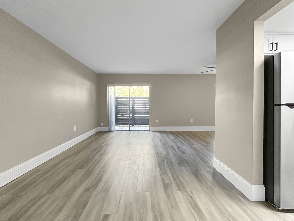 A room with light wood flooring and a sliding glass door.
