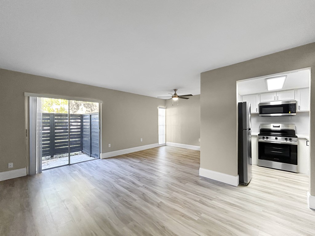 A spacious living room with a sliding glass door leading to a balcony.