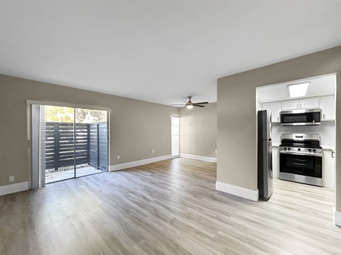 A spacious living room with a sliding glass door leading to a balcony.