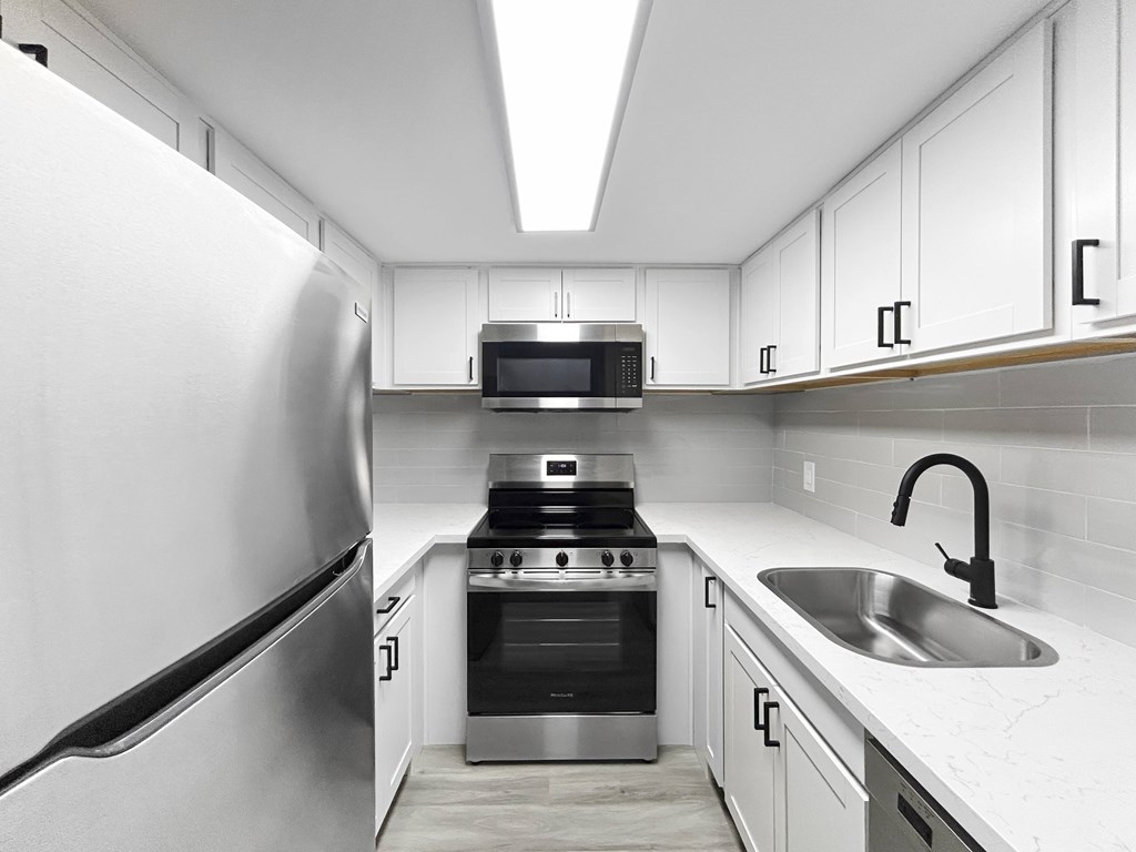 A modern kitchen with a stainless steel refrigerator and a stove top oven.