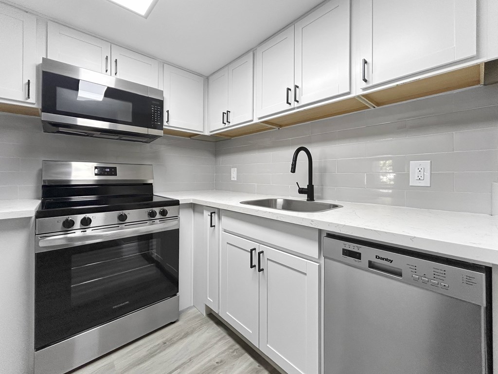 A modern kitchen with white cabinets and stainless steel appliances.