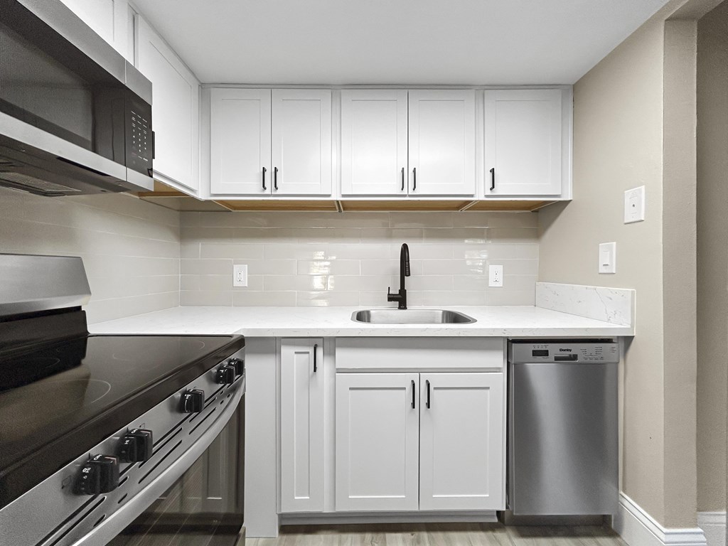 A kitchen with white cabinets and a black stove top oven.