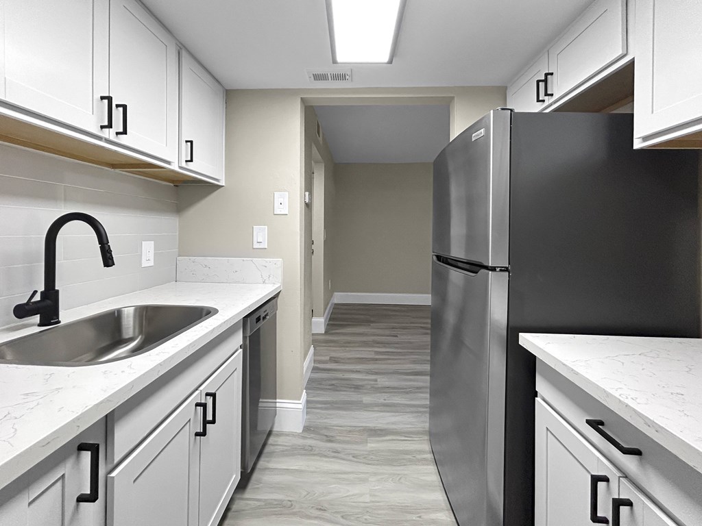 A kitchen with a black refrigerator and white cabinets.