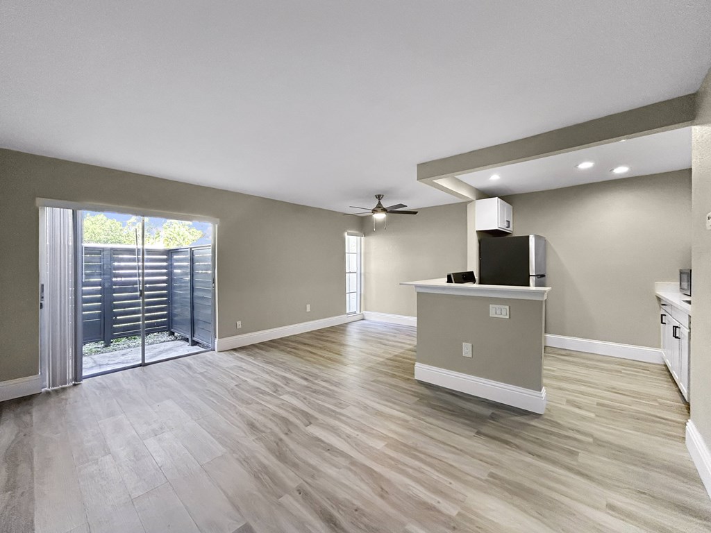 A spacious room with a television on a cabinet and a ceiling fan.
