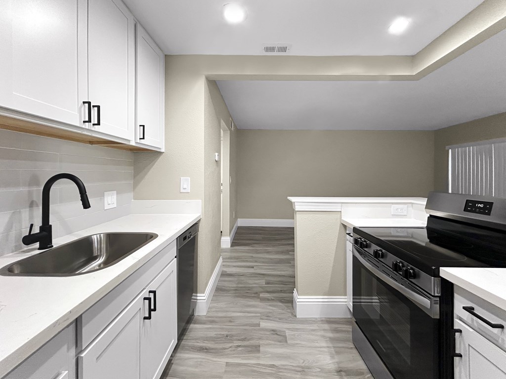 A kitchen with a black stove top oven and a white counter top.