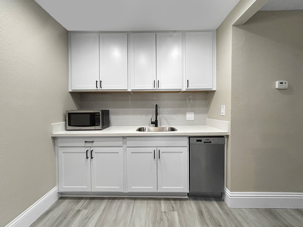 A kitchen with white cabinets and a microwave above the sink.