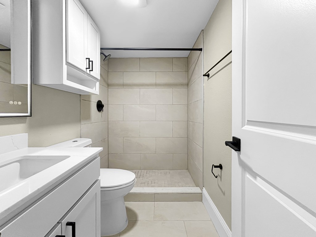 A white bathroom with a toilet, sink, and shower.