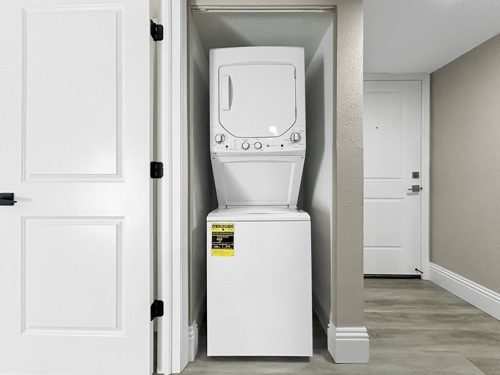 A white tankless water heater is installed in a narrow hallway.