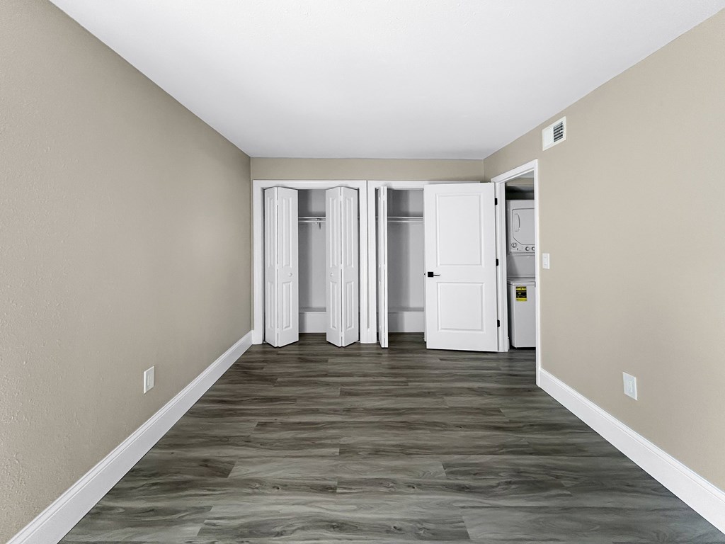 A long hallway with a white door on the right and a white refrigerator in the distance.