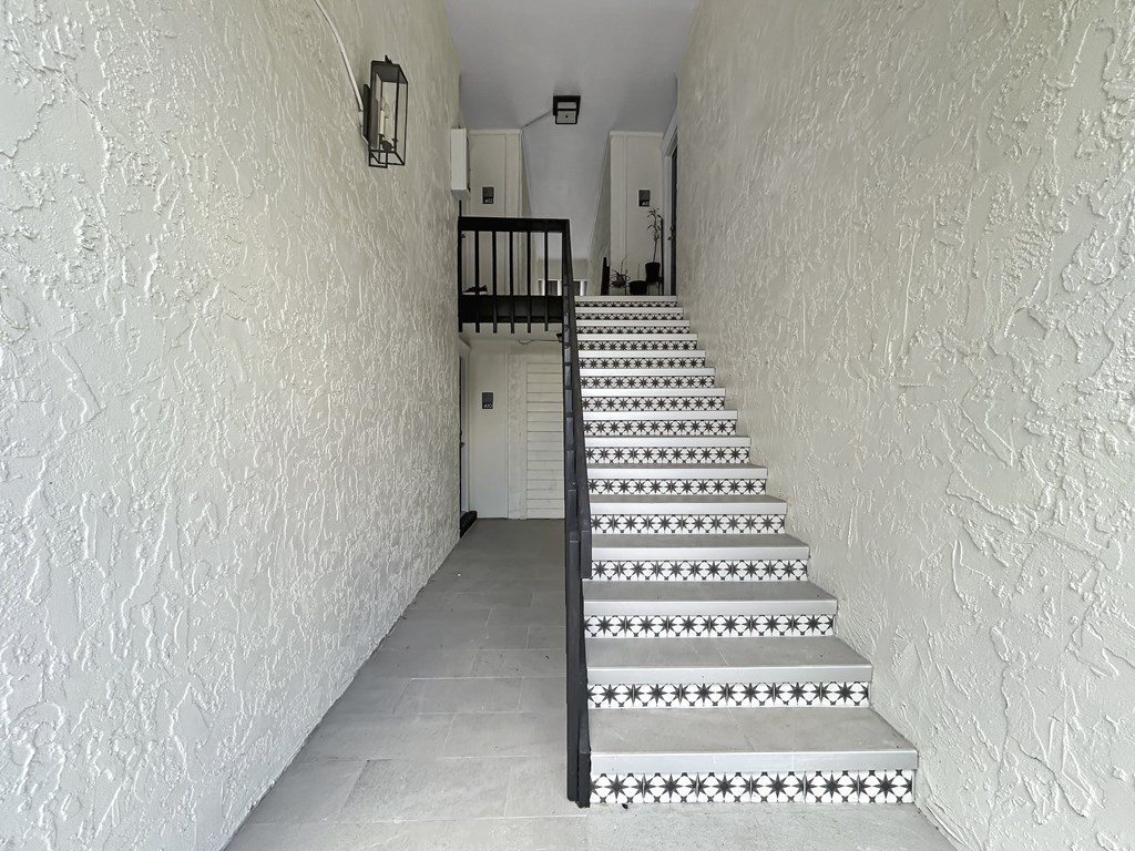 A staircase with a black railing and a white tiled floor.