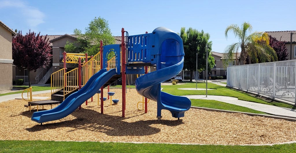 A playground with a blue slide and a yellow railing.