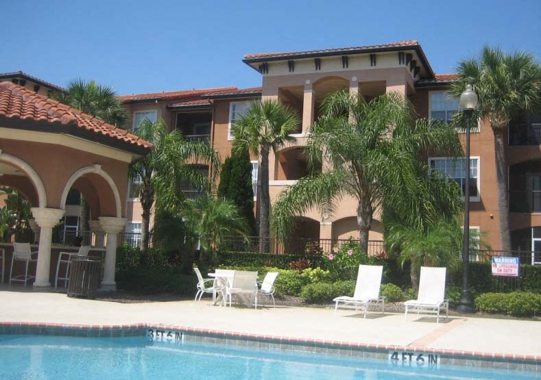 a swimming pool with chairs in front of a building