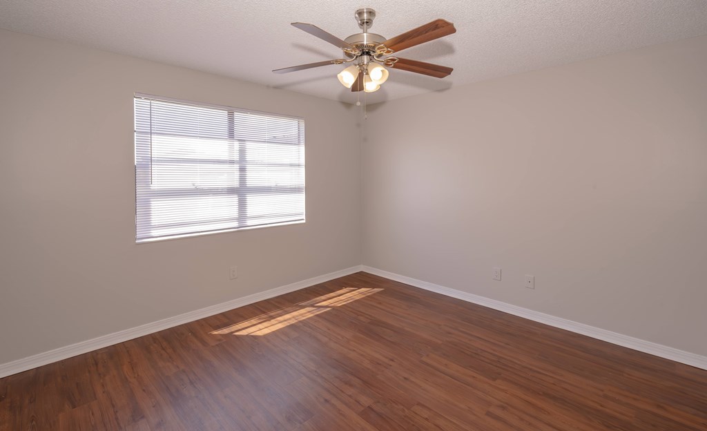 A room with a ceiling fan and wooden flooring.