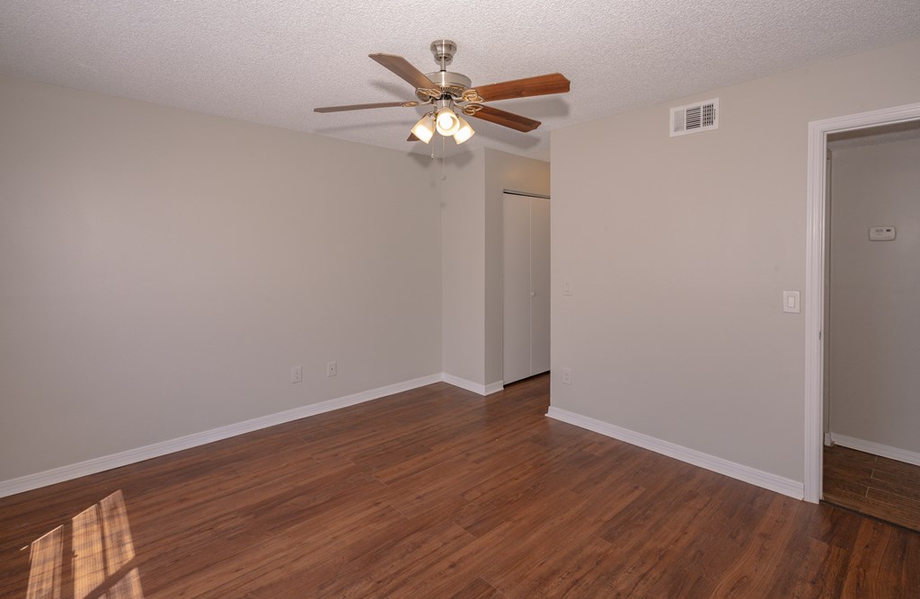 A room with a ceiling fan and wooden floors.