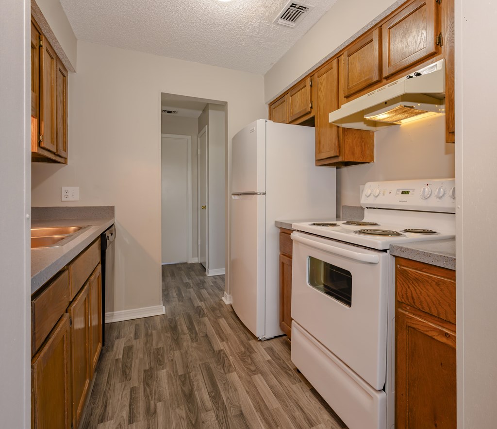 A kitchen with a white stove top oven and white refrigerator.