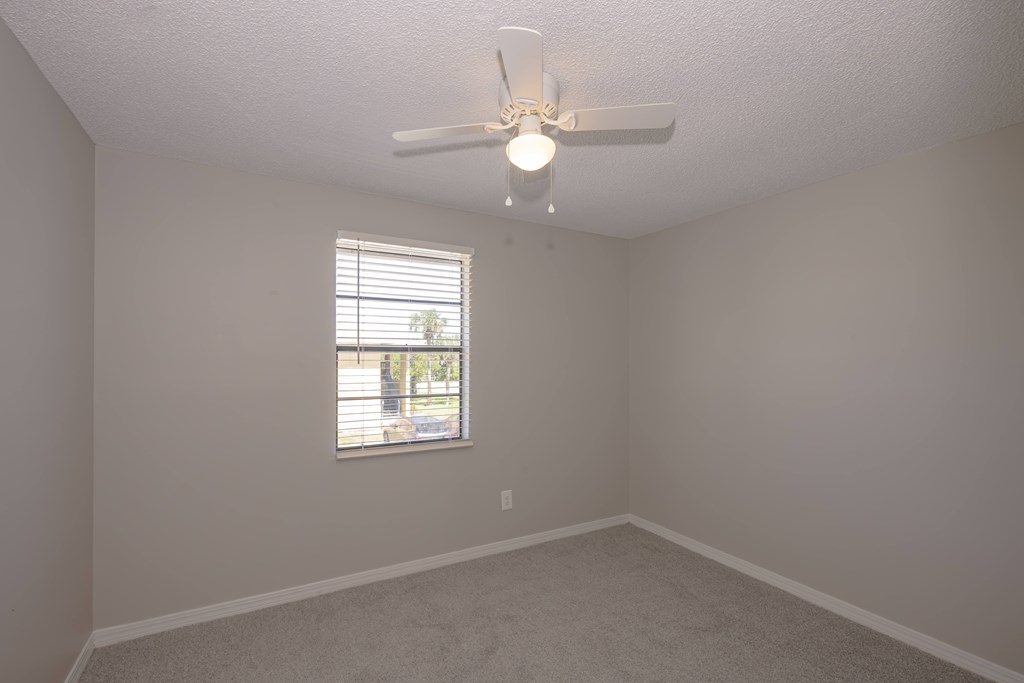 A room with a ceiling fan and a window with blinds.