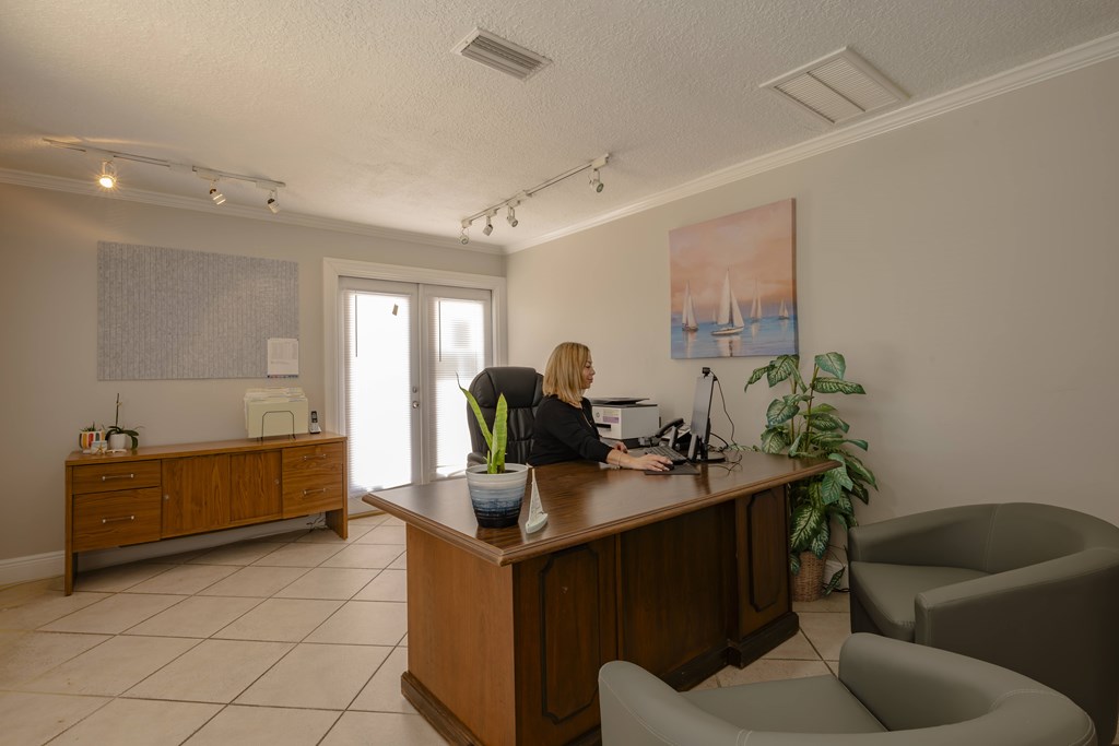 A woman is sitting at a reception desk in a well-lit office.