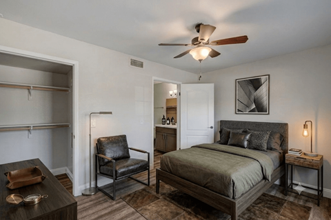 A bedroom with a bed, chair, and a ceiling fan.