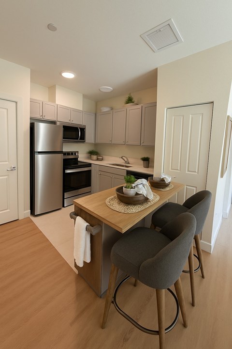 A kitchen with a table and chairs in the foreground and a refrigerator, oven, and microwave in the background.