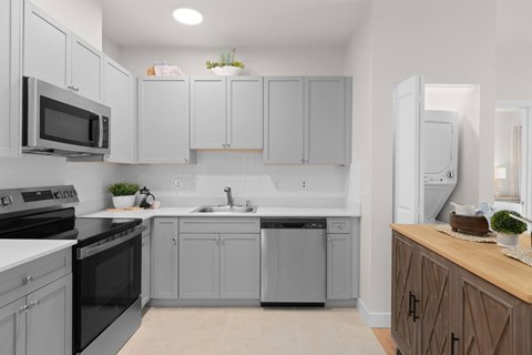 A kitchen with grey cabinets and black appliances.