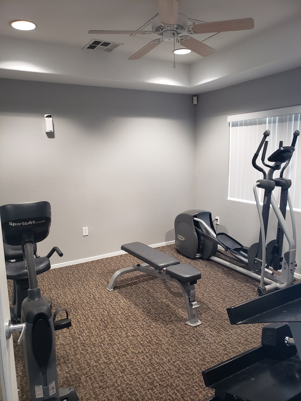 A home gym with a variety of equipment including a treadmill, weights, and a bench.