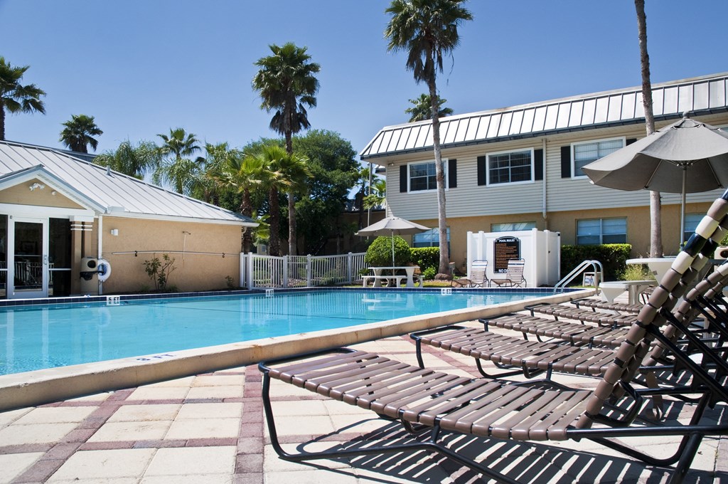 a swimming pool with lounge chairs in front of a building