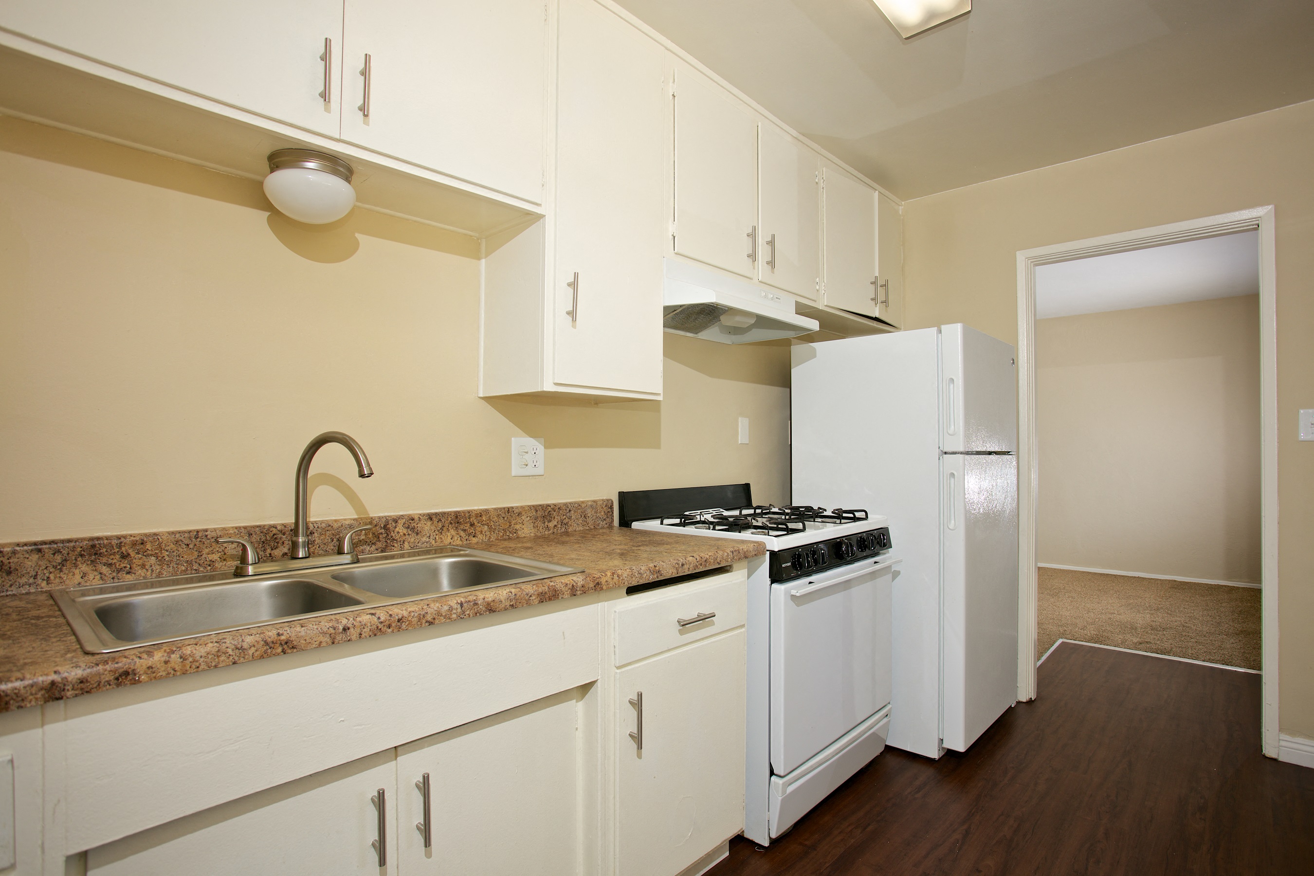 a kitchen with white cabinets and a sink and a refrigerator