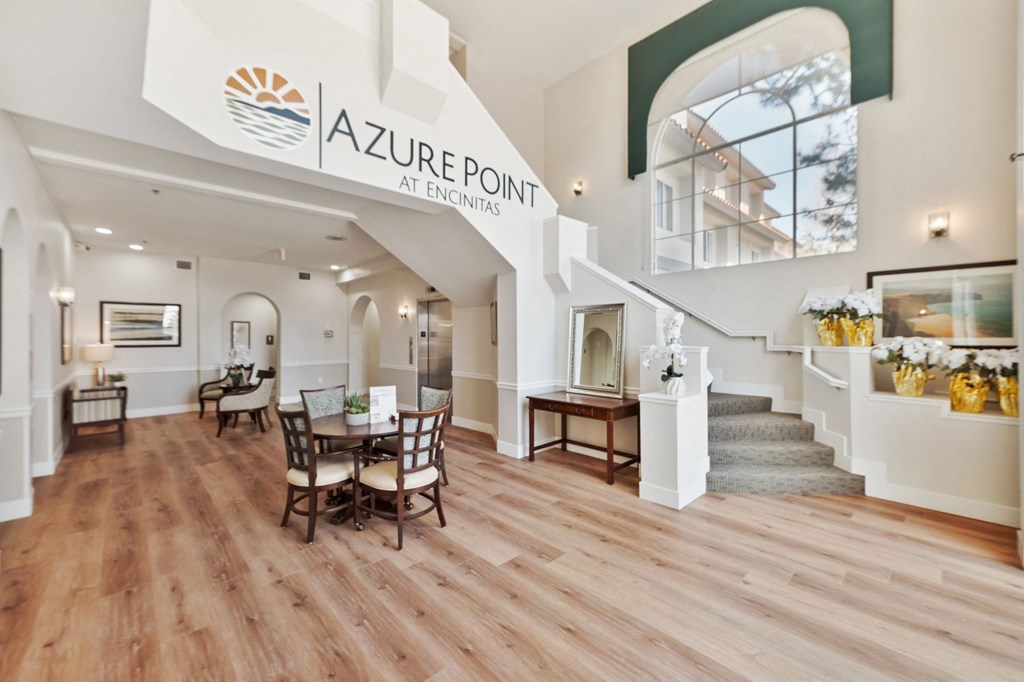 an open concept living room and dining room with hardwood flooring and a large sign at Azure Point at Encinitas, Encinitas