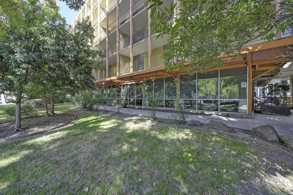 a building with a lawn and trees in front of it at The Riverview (55+), California, 95814