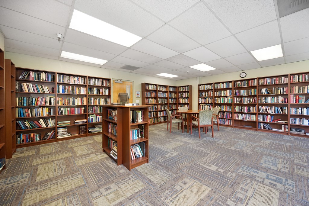 a library with shelves of books and a table and chairs at The Riverview (55+), California