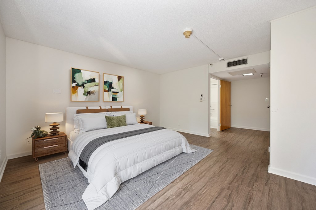 a bedroom with white walls and wood floors and a bed at The Riverview (55+), Sacramento, CA