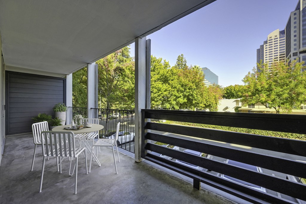 a patio with a table and chairs on a balcony at The Riverview (55+), Sacramento, 95814