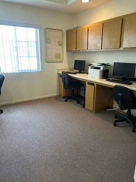 A room with a desk, chairs, and a printer.