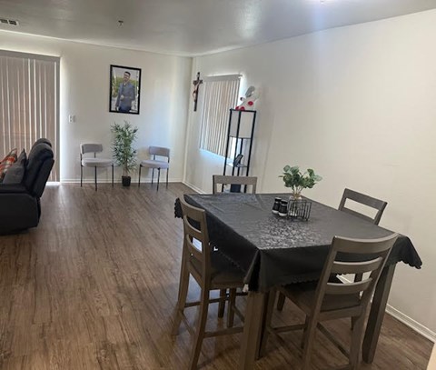 A dining room with a table set for two and a couch.