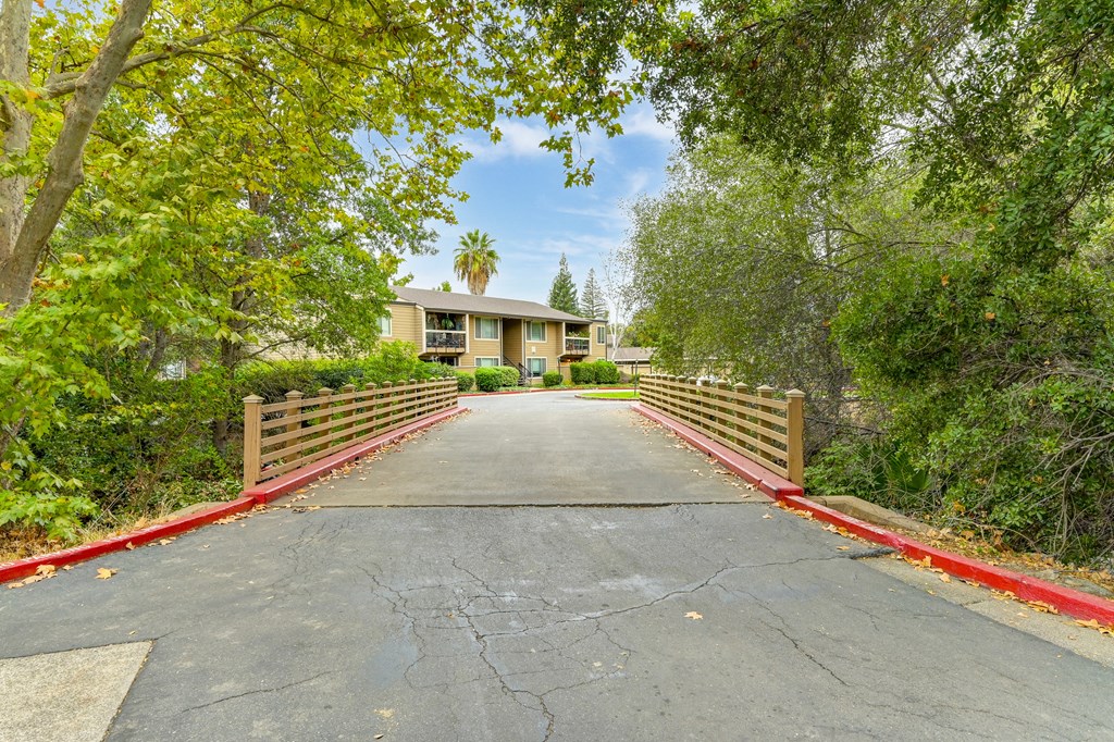 a bridge over a road with a house in the background