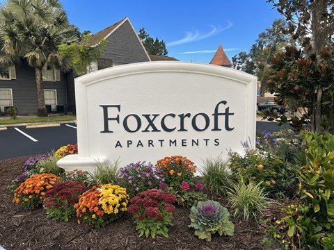 A sign for Foxcroft Apartments is surrounded by flowers.