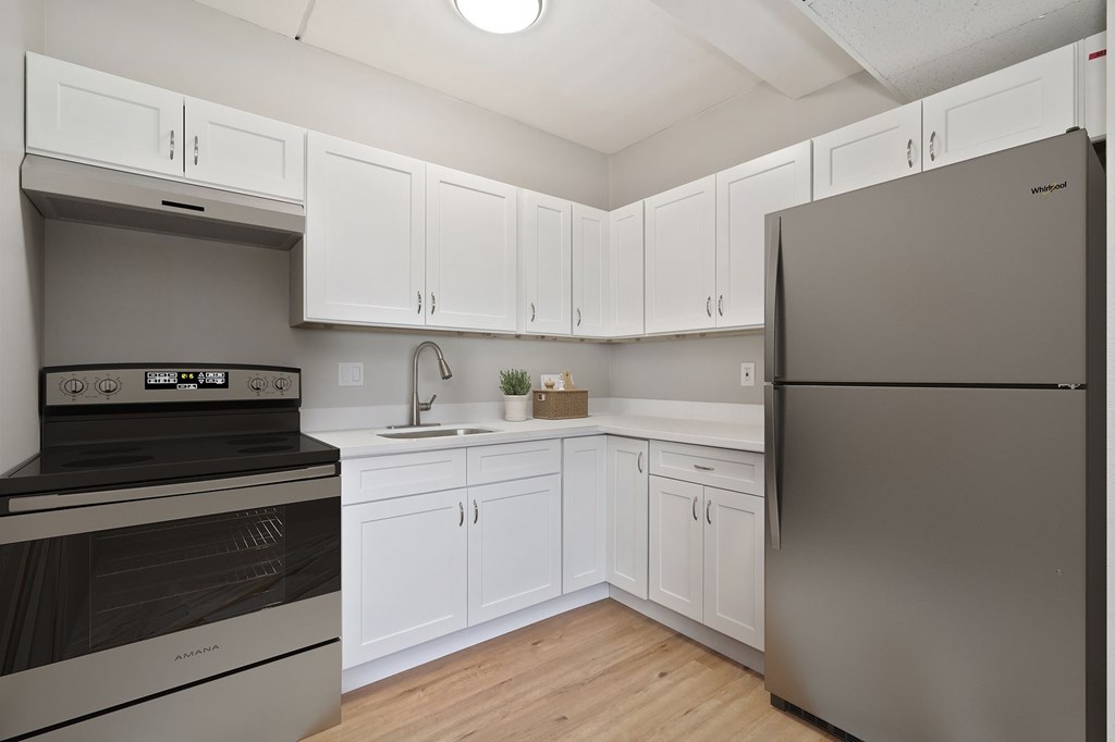 A kitchen with white cabinets and a stainless steel refrigerator.