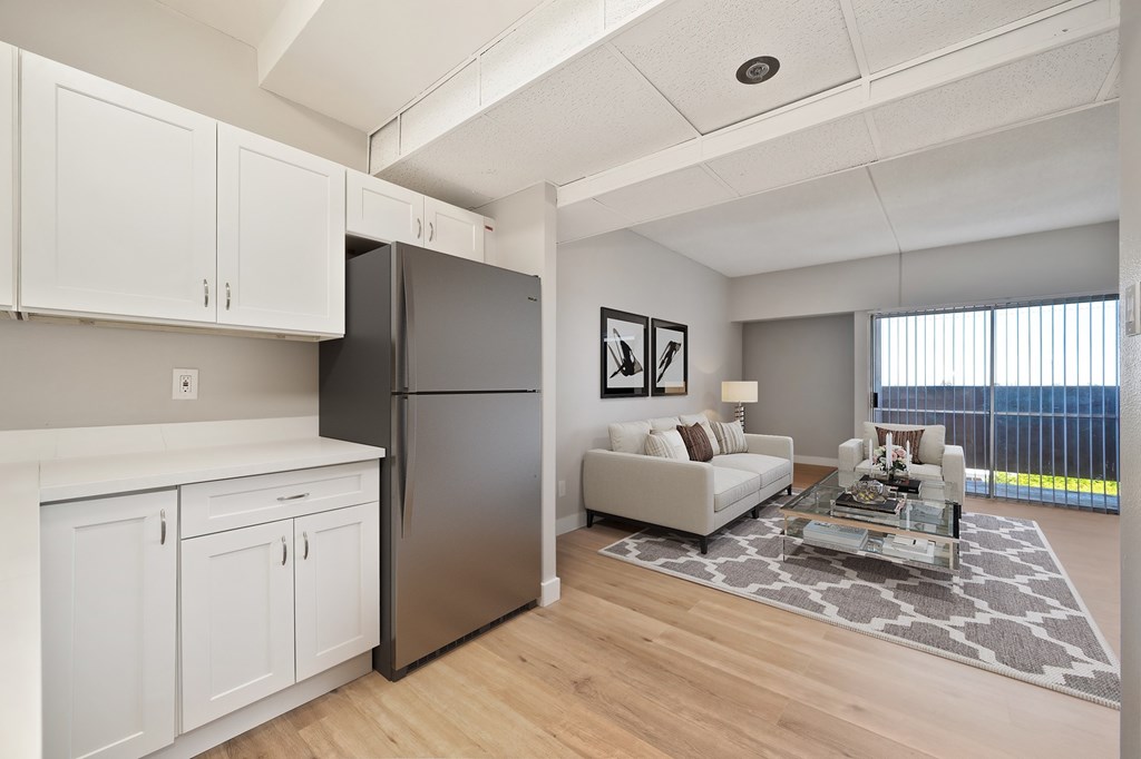A modern kitchen with white cabinets and a black refrigerator.