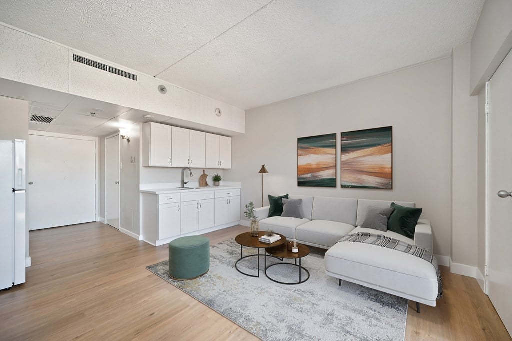 A living room with a white couch and a green ottoman.