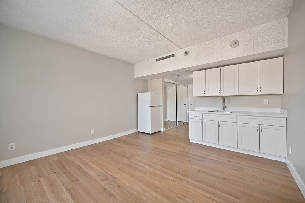 A kitchen with white cabinets and a wooden floor.