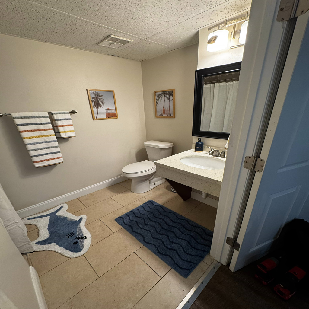A bathroom with a toilet, sink, and mirror.