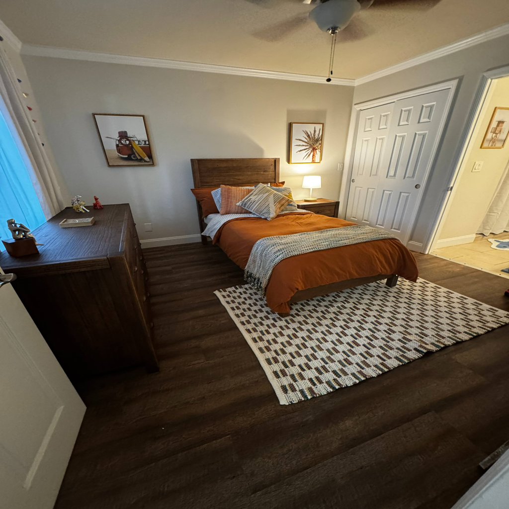 A bedroom with a bed, nightstand, and a ceiling fan.