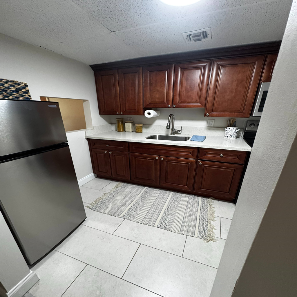 A kitchen with brown cabinets and a black refrigerator.